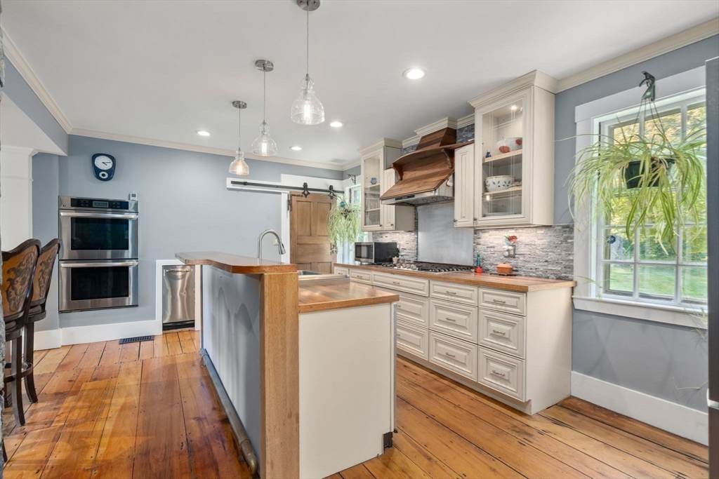 100 Eliot Street Natick, MA 01760 - Photo 7 of 41 a kitchen with stainless steel appliances granite countertop a refrigerator a sink dishwasher a stove and white countertops with wooden floor