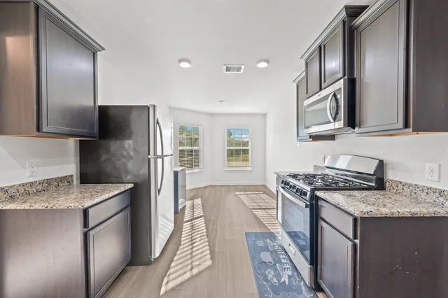 a kitchen with stainless steel appliances granite countertop a sink stove and refrigerator
