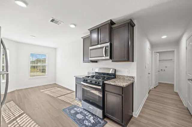 a kitchen with granite countertop stainless steel appliances a stove sink and microwave