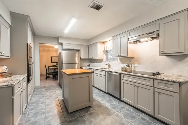 a kitchen with stainless steel appliances granite countertop a refrigerator a stove a sink and a refrigerator