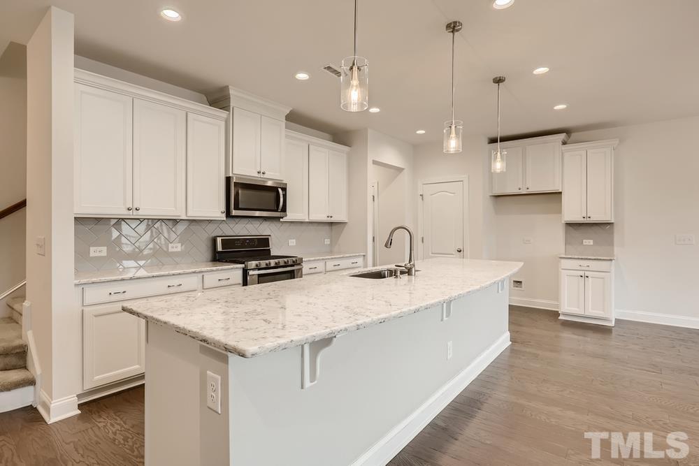 1207 Catch Fly Lane Durham, NC 27713 - Photo 7 of 28 a kitchen with a sink a stove a microwave a center island and cabinets