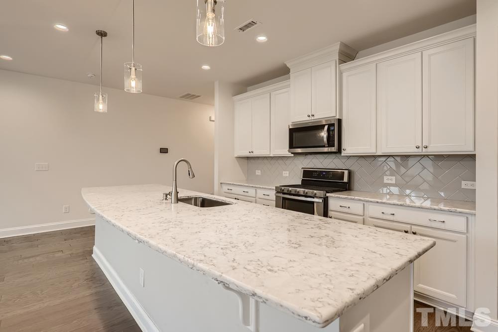 1207 Catch Fly Lane Durham, NC 27713 - Photo 8 of 28 a kitchen with kitchen island a sink stainless steel appliances and white cabinets