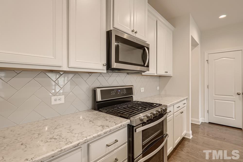 1207 Catch Fly Lane Durham, NC 27713 - Photo 10 of 28 a kitchen with granite countertop white cabinets and a stove top oven