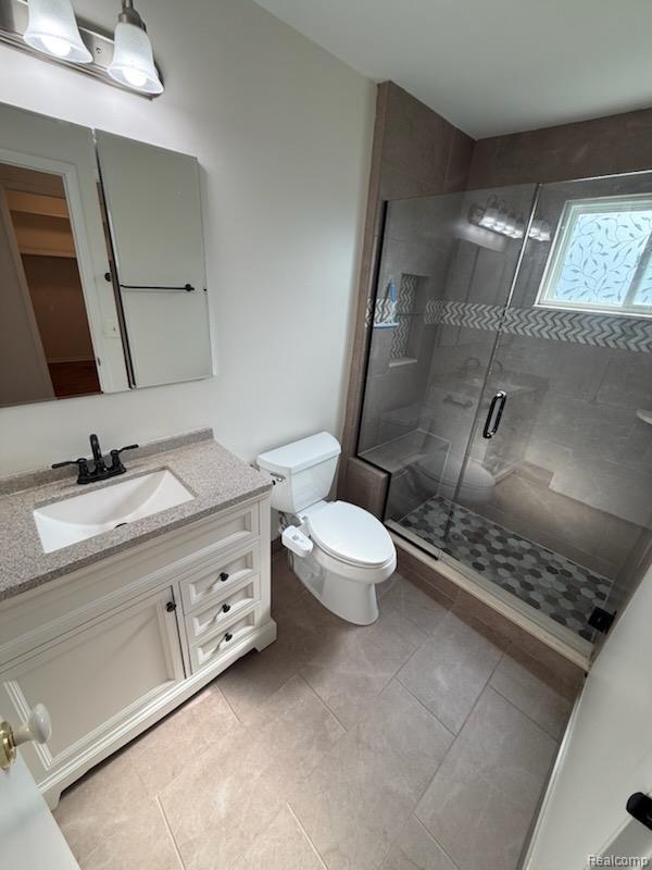 28144 Yorktown Road Farmington, MI 48331 - Photo 17 of 25 Bathroom featuring a glass-enclosed shower with a mosaic tile floor, white vanity with a light-colored countertop, and a built-in shower niche with decorative tiling
