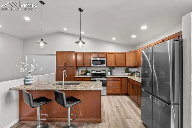 a kitchen with kitchen island granite countertop a sink refrigerator and cabinets