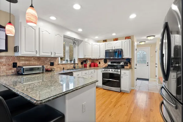 a kitchen with stainless steel appliances granite countertop a stove refrigerator and a sink