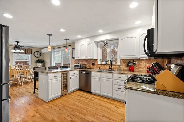 a kitchen with stainless steel appliances granite countertop a stove top oven a sink dishwasher and a refrigerator with wooden floor