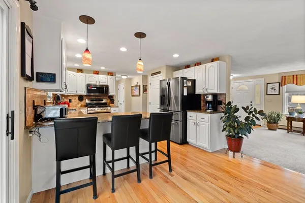a kitchen with stainless steel appliances a dining table chairs stove refrigerator and cabinets
