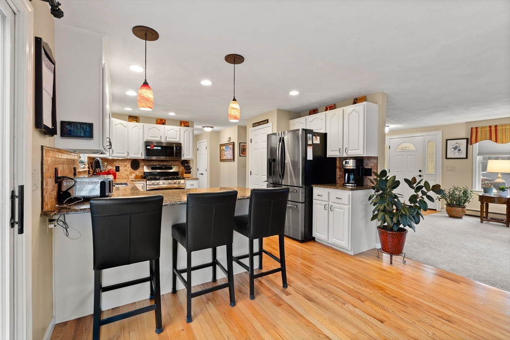 27 Folger Avenue Beverly, MA 01915 - Photo 6 of 34 a kitchen with stainless steel appliances a dining table chairs stove refrigerator and cabinets