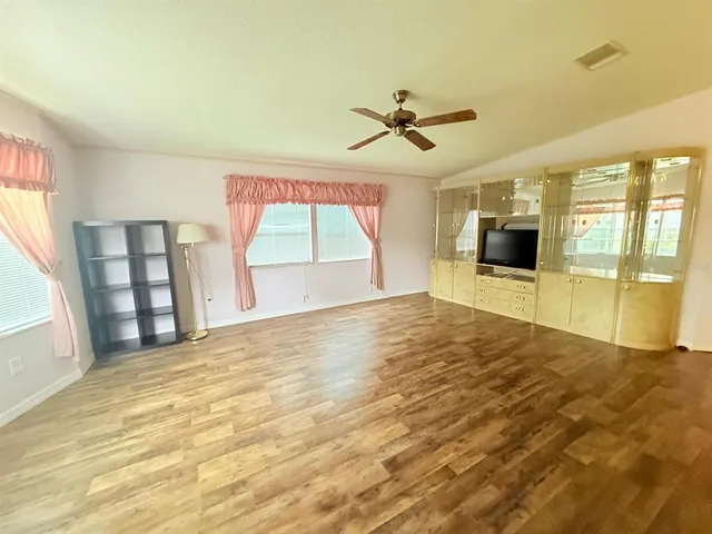 a view of empty room with wooden floor and fan