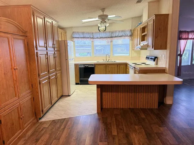 a kitchen with a refrigerator a sink and wooden floor