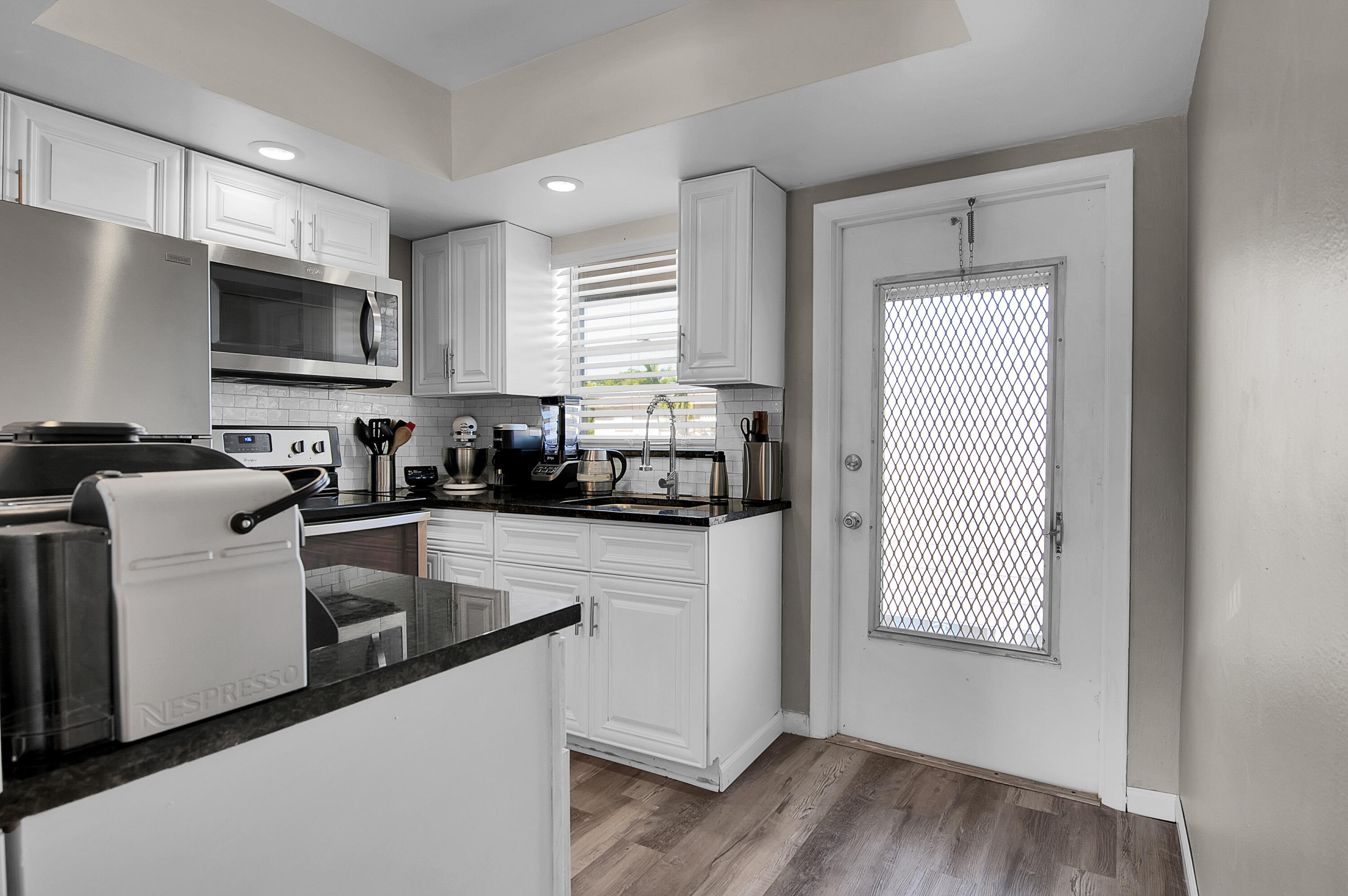 312 Northeast 17th Avenue, Unit 202 Boynton Beach, FL 33435 - Photo 11 of 44 a kitchen with granite countertop cabinets stainless steel appliances a sink and a window