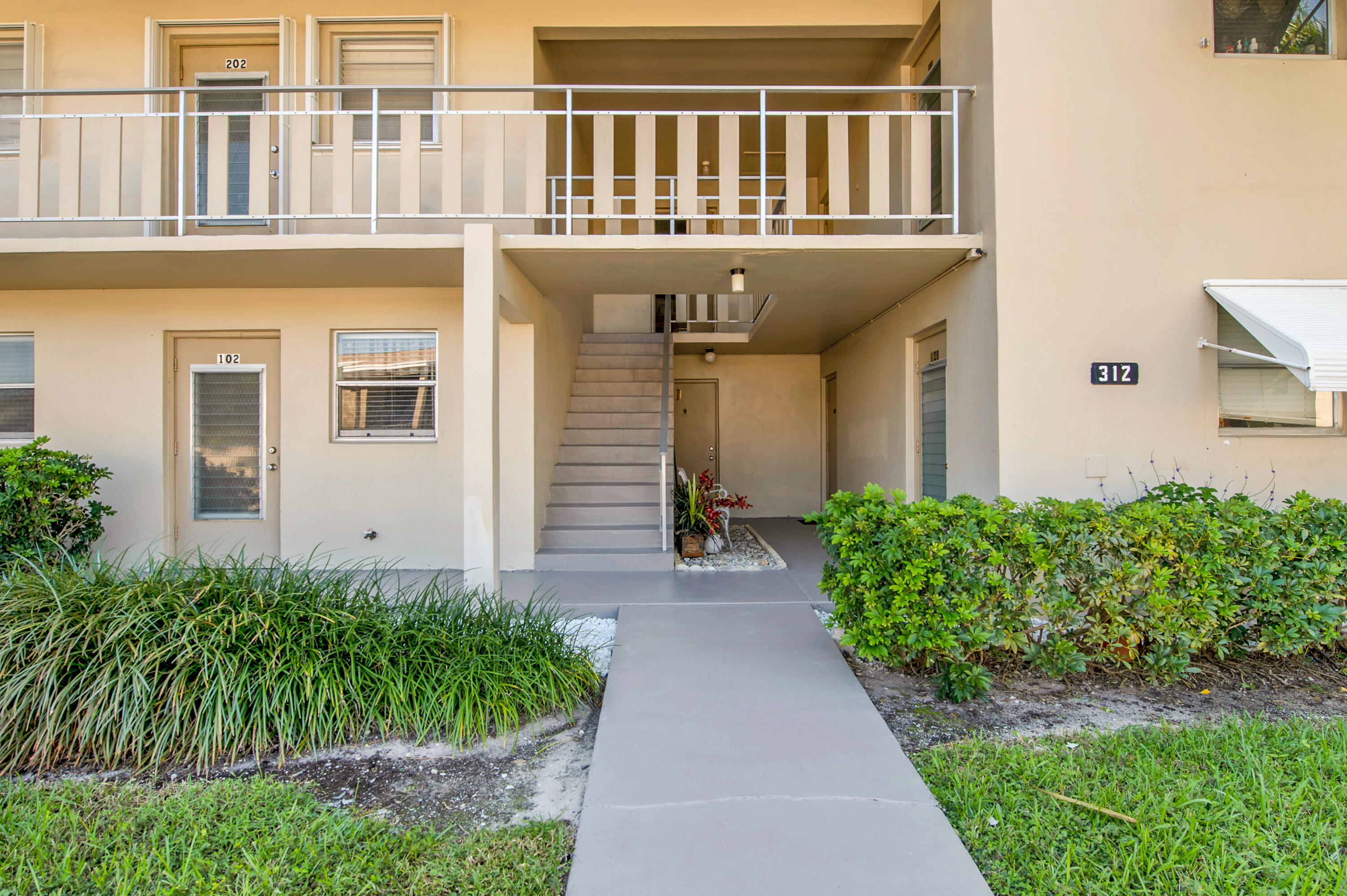 312 Northeast 17th Avenue, Unit 202 Boynton Beach, FL 33435 - Photo 37 of 44 a front view of a house with garden and plants