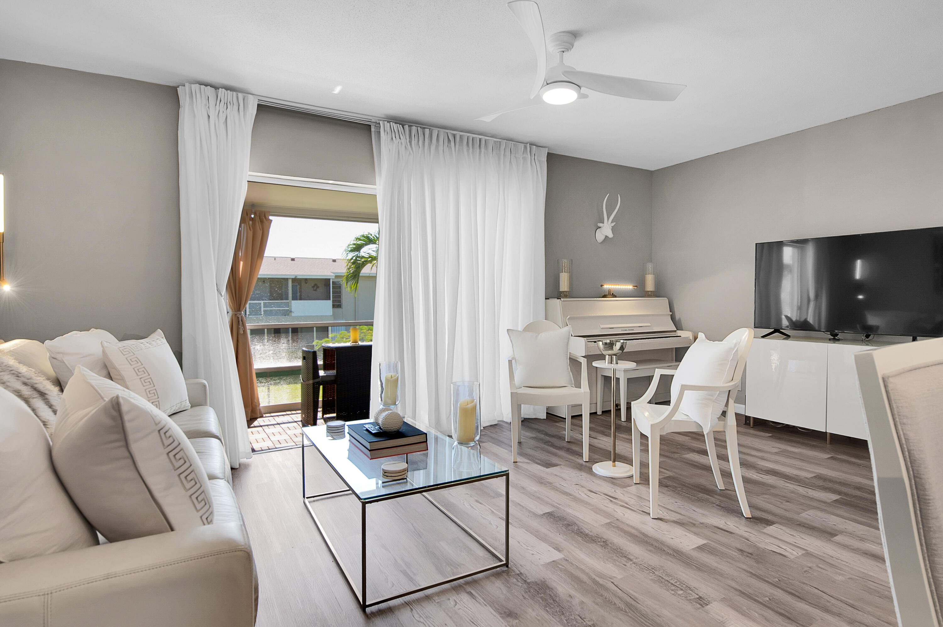 312 Northeast 17th Avenue, Unit 202 Boynton Beach, FL 33435 - Photo 8 of 44 a living room with furniture a flat screen tv and a floor to ceiling window