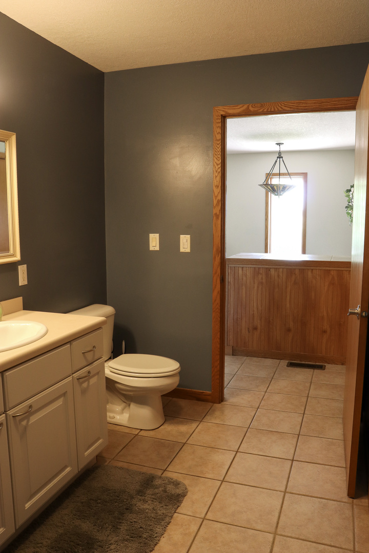 16181 Sand Road Fulton, IL 61252 - Photo 18 of 57 a bathroom with a toilet a sink a vanity and mirror