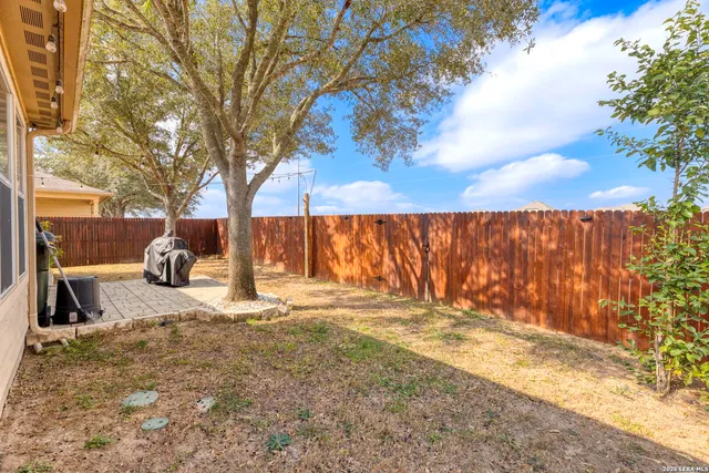 a backyard of a house with table and chairs under an umbrella