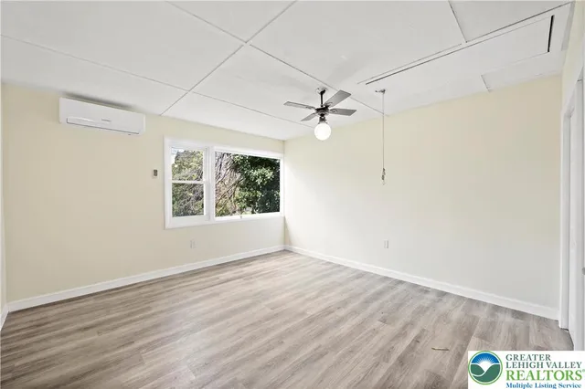 an empty room with wooden floor chandelier fan and windows
