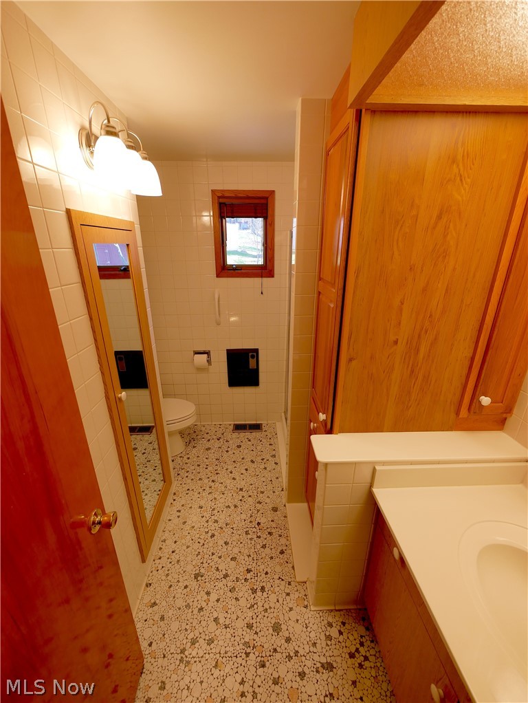 57500 Hospital Road Bellaire, OH 43906 - Photo 14 of 22 Bathroom with tile walls, walk in shower, toilet, and vanity
