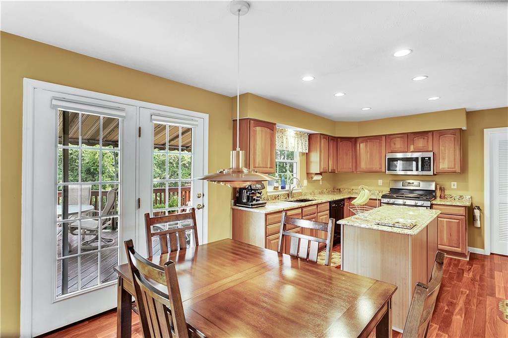 229 Field Club Circle McKees Rocks, PA 15136 - Photo 6 of 34 a kitchen with stainless steel appliances kitchen island granite countertop a stove top oven a sink a dining table and chairs with wooden floor