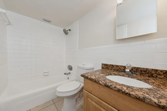 a bathroom with a granite countertop sink a toilet and bathtub