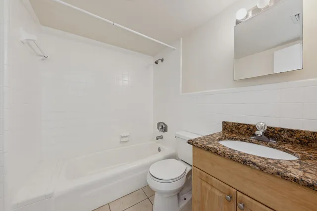 a bathroom with a granite countertop toilet a sink and bathtub