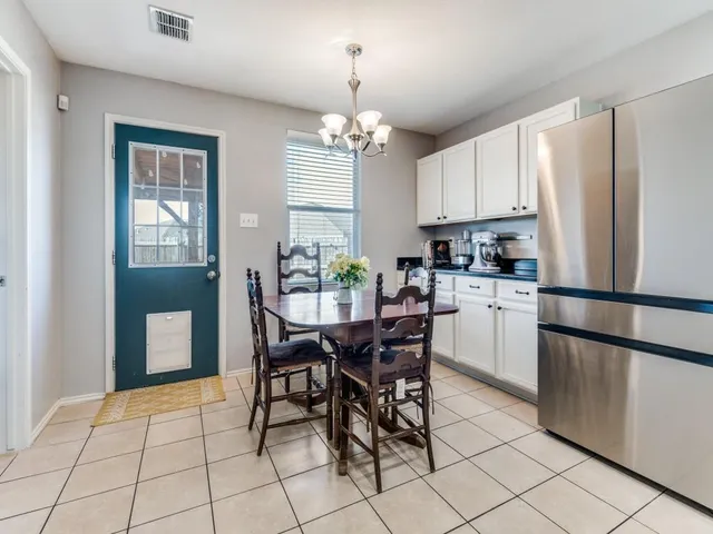 a kitchen with stainless steel appliances granite countertop a dining table chairs refrigerator and cabinets