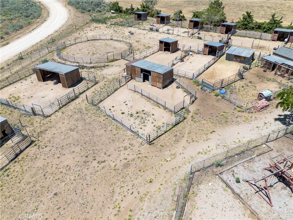 10960 Steinhoff Road Frazier Park, CA 93225 - Photo 9 of 46 An elevated aerial perspective highlighting the property's equestrian setup, featuring multiple horse stalls, covered shelters, fenced corrals, and open paddocks.