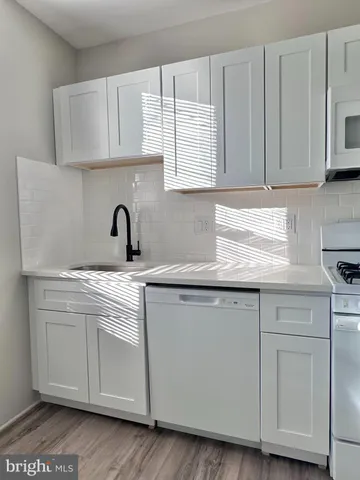 a kitchen with white cabinets and sink