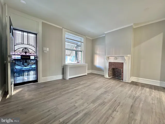 an empty room with wooden floor fireplace and windows