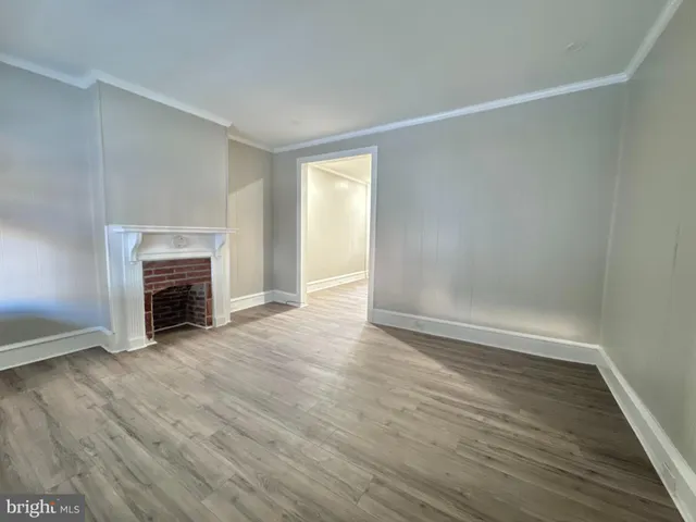 an empty room with wooden floor fireplace and windows