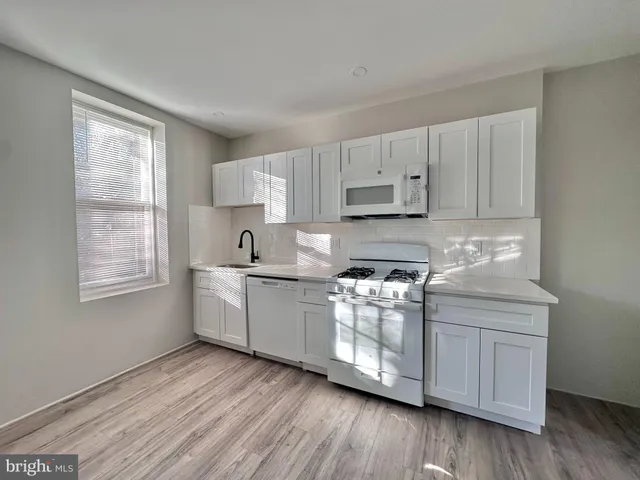 a kitchen with stainless steel appliances white cabinets and wooden floors