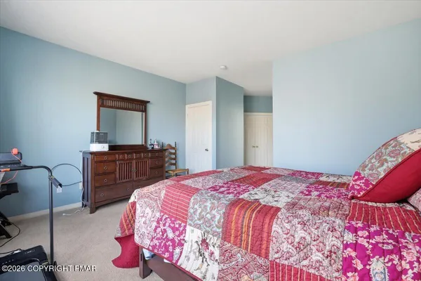 a bedroom with a bed and dresser with mirror