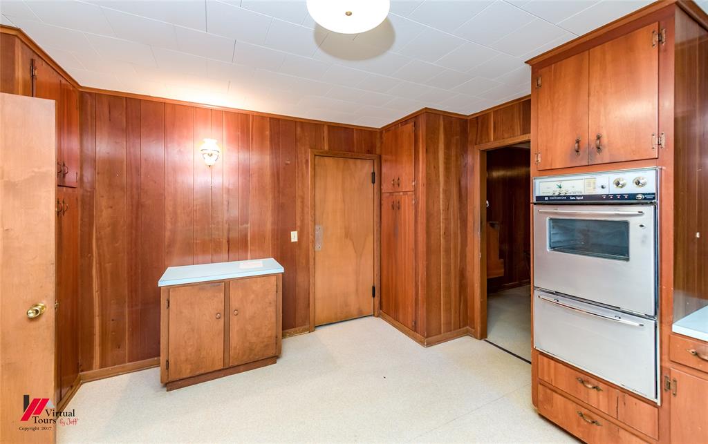205 7th Street Northeast Springhill, LA 71075 - Photo 11 of 40 Paneled walls, built-in cabinetry, wall-mounted oven, and cream-colored flooring