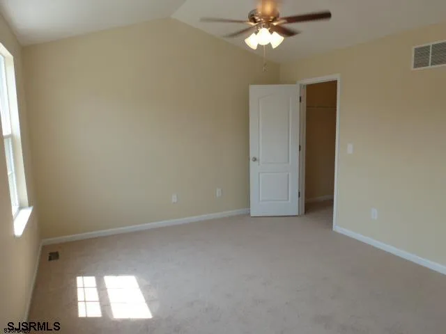 an empty room with a chandelier fan and windows
