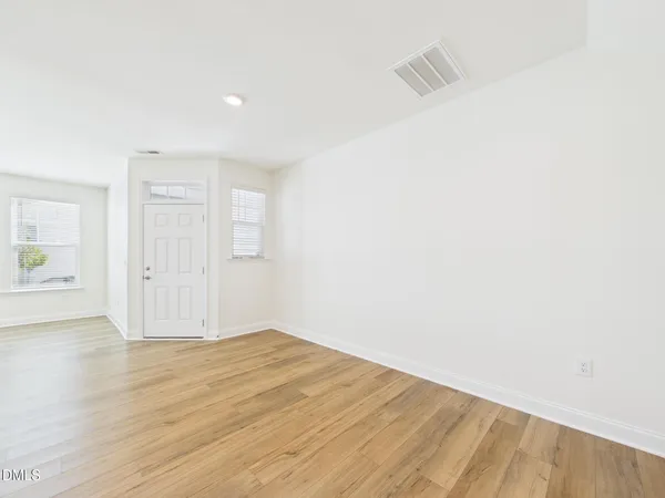 a large kitchen with stainless steel appliances granite countertop a stove a sink a refrigerator and white cabinets with wooden floor