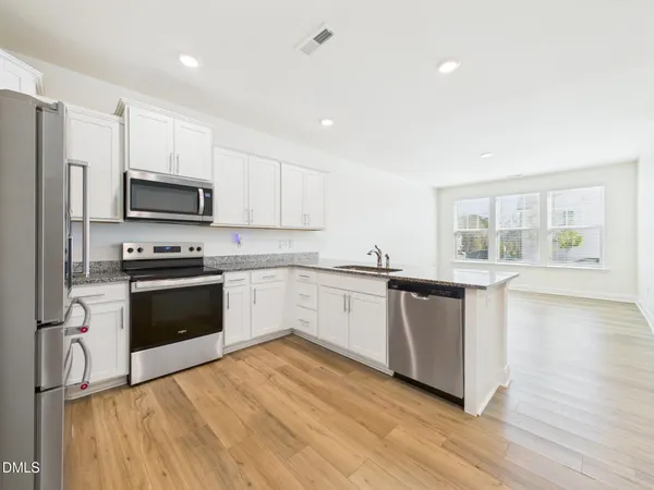 a kitchen with granite countertop white cabinets and wooden floor