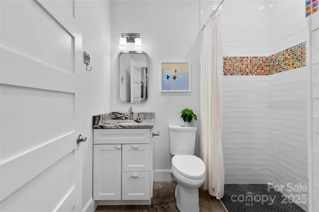 a bathroom with a granite countertop toilet sink and mirror
