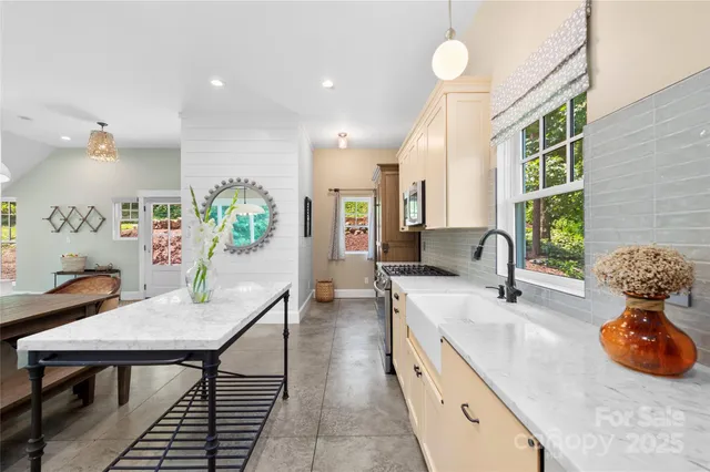 a kitchen with stainless steel appliances granite countertop a stove a sink a dining table and chairs with wooden floor