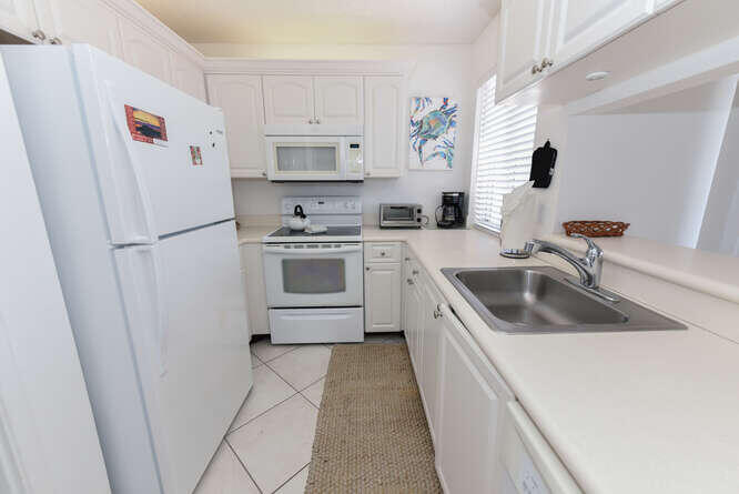 353 Highway 1, Unit F306 Jupiter, FL 33477 - Photo 9 of 43 a kitchen with a sink a refrigerator and cabinets