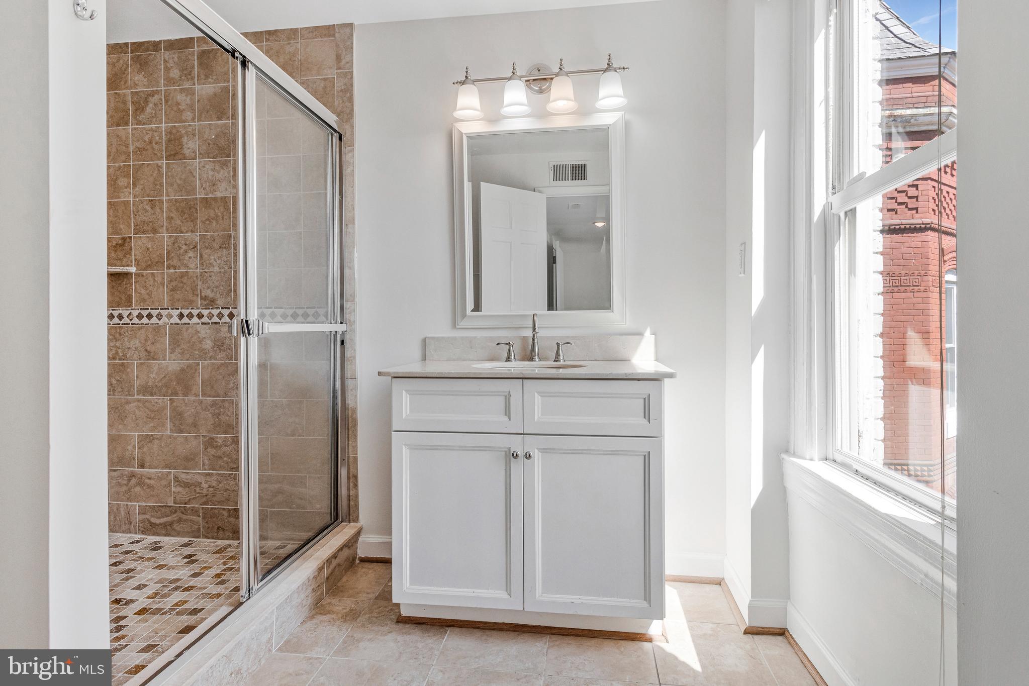 334 E Street Northeast Washington, DC 20002 - Photo 23 of 32 a bathroom with a granite countertop sink a mirror and a shower