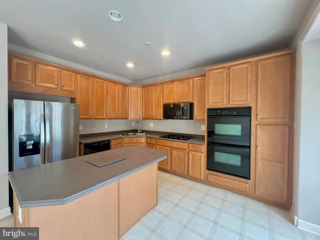 a kitchen with stainless steel appliances granite countertop a refrigerator stove top oven and sink