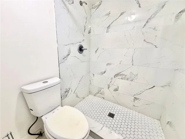 a white toilet sitting next to a bathroom sink and a shower