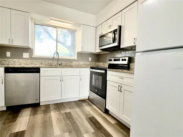 a kitchen with stainless steel appliances granite countertop a sink a stove and microwave