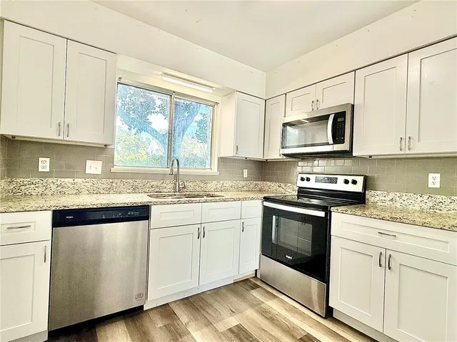 a kitchen with stainless steel appliances granite countertop a stove a sink and a microwave
