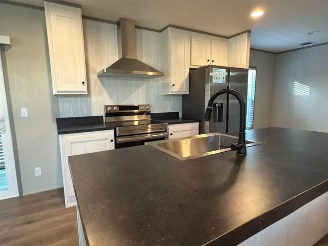 a kitchen with stainless steel appliances granite countertop a sink a stove and a refrigerator