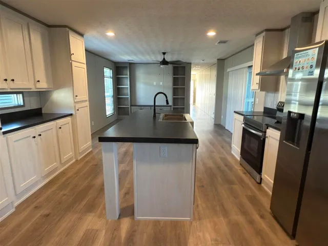 a kitchen with granite countertop a stove a sink a refrigerator and wooden floor