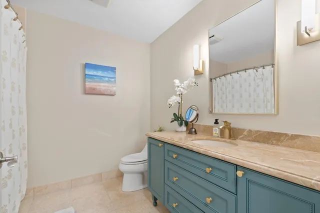 a bathroom with a granite countertop toilet sink and mirror