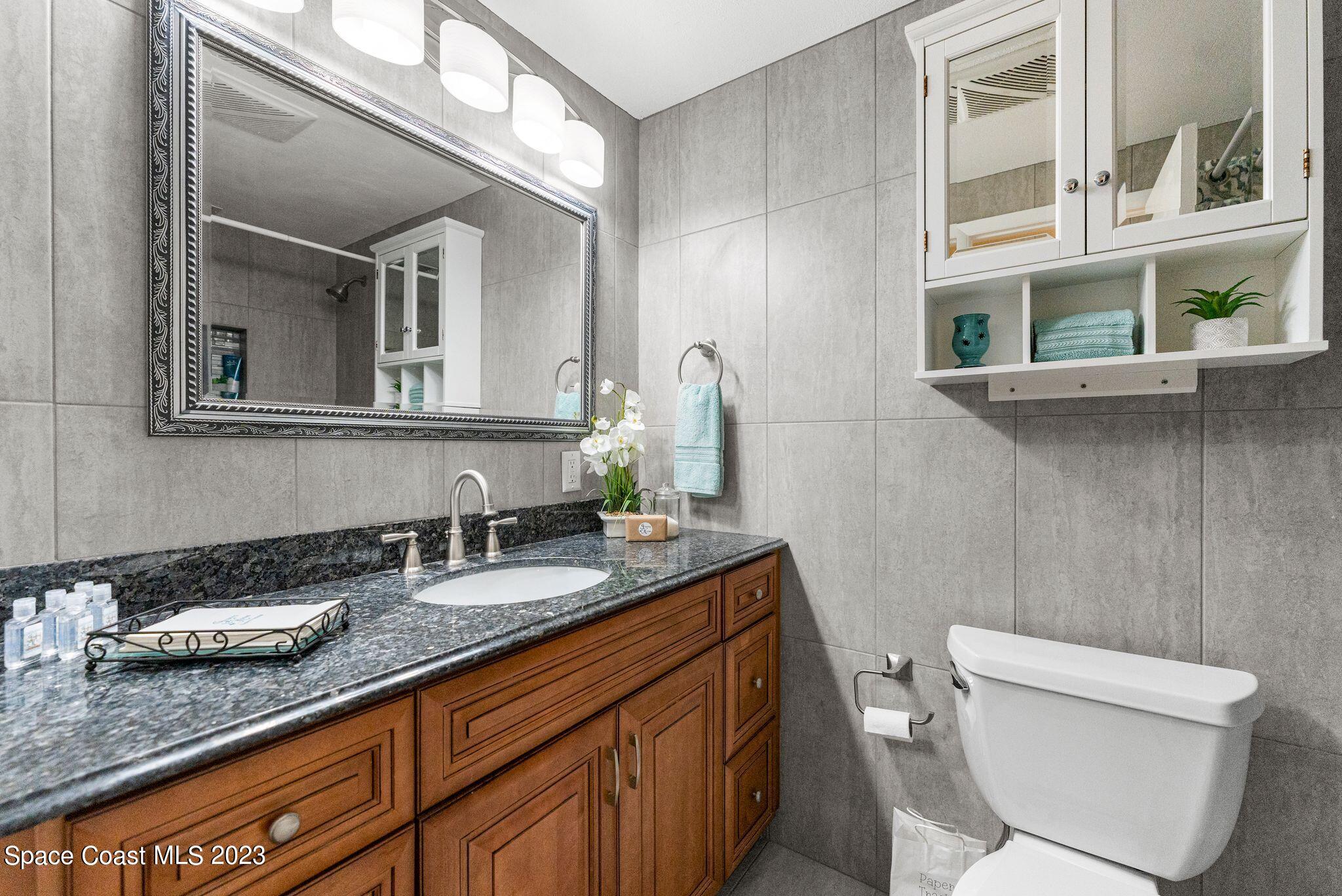 2007 Oak Street Melbourne Beach, FL 32951 - Photo 12 of 26 a bathroom with a granite countertop toilet sink and mirror