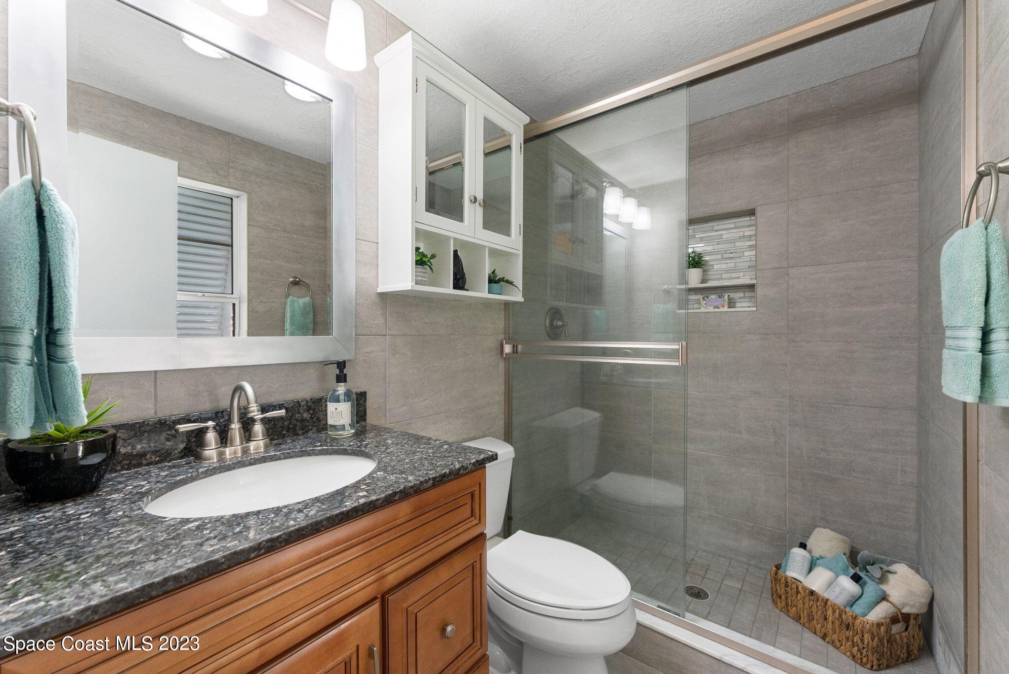 2007 Oak Street Melbourne Beach, FL 32951 - Photo 10 of 26 a bathroom with a granite countertop sink toilet and shower