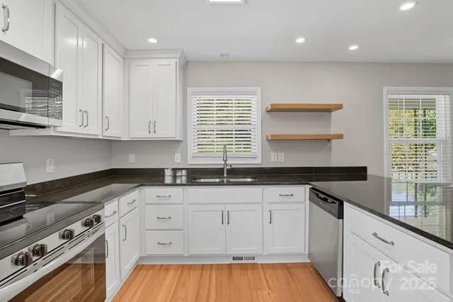 a kitchen with granite countertop white cabinets and a stove